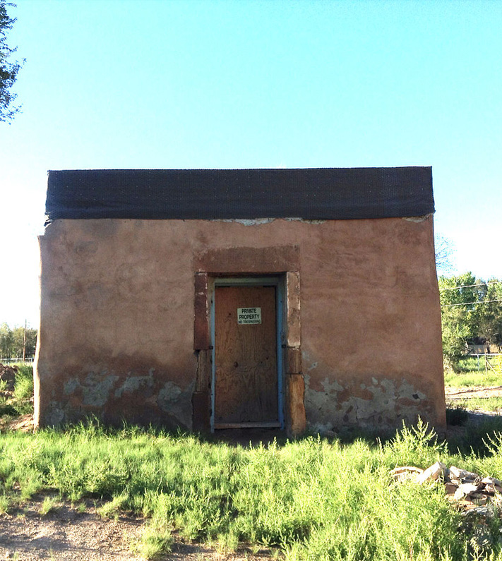 an image of a small square building in a field located in Tome, New Mexico.