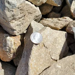 Mist 2 - 4 gravel, an exquisite collection of textured stones in delicate gray hues, gracefully displayed alongside a quarter for size reference. Available exclusively at Albuquerque Landscape Supply, this premium-grade gravel imbues your outdoor space with an enchanting aura. Employ this versatile material to craft enchanting pathways, captivating garden accents, or as a defining feature that elevates your landscape design with its ethereal charm.